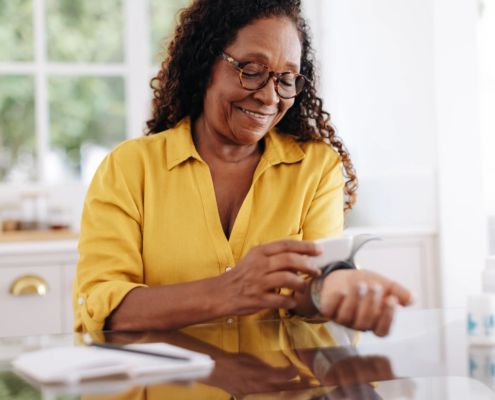 Senior woman measuring her blood pressure with a medical device, monitoring the readings carefully.